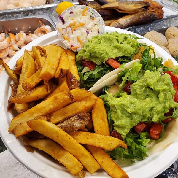 Shore Fresh Seafood Market & Restaurant's fish tacos with guacamole, fries, and coleslaw on a white plate.
